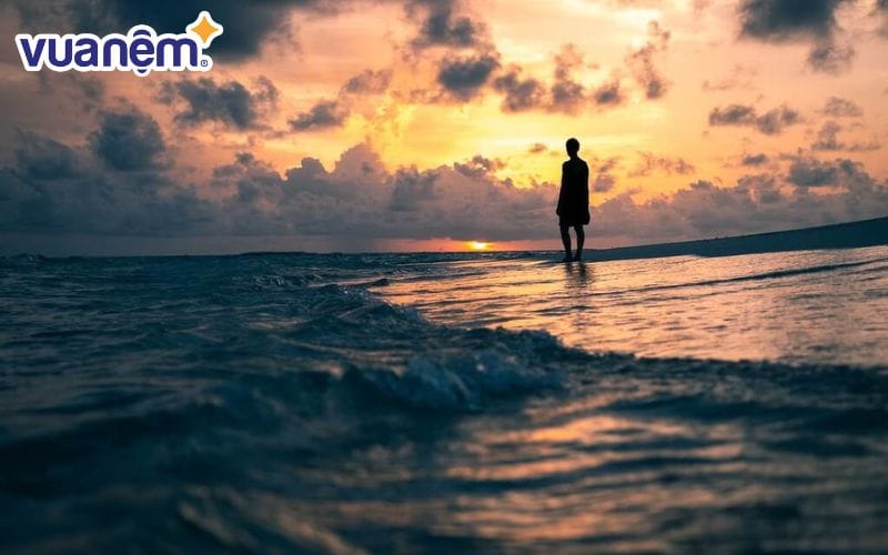 Giữa hoàng hôn, con người lặng thinh ngắm nhìn từng đợt sóng êm ả vỗ bờ.