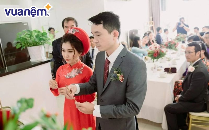 Đôi vợ chồng trẻ thắp hương trên bàn thờ gia tiên nhà gái