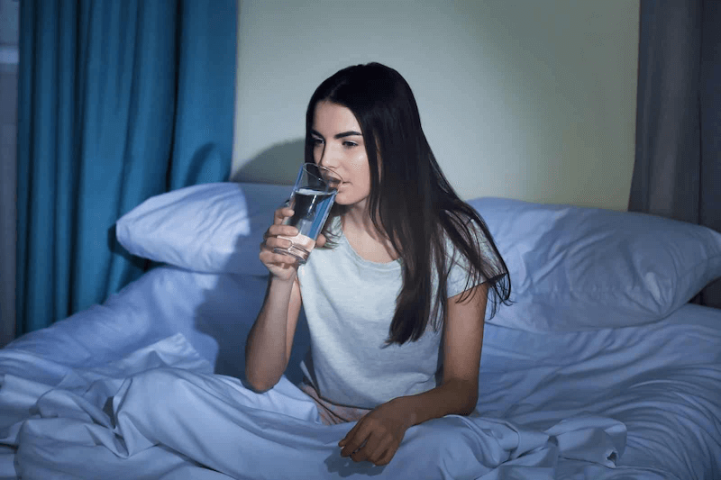 Cô gái ở trên giường đang uống nước