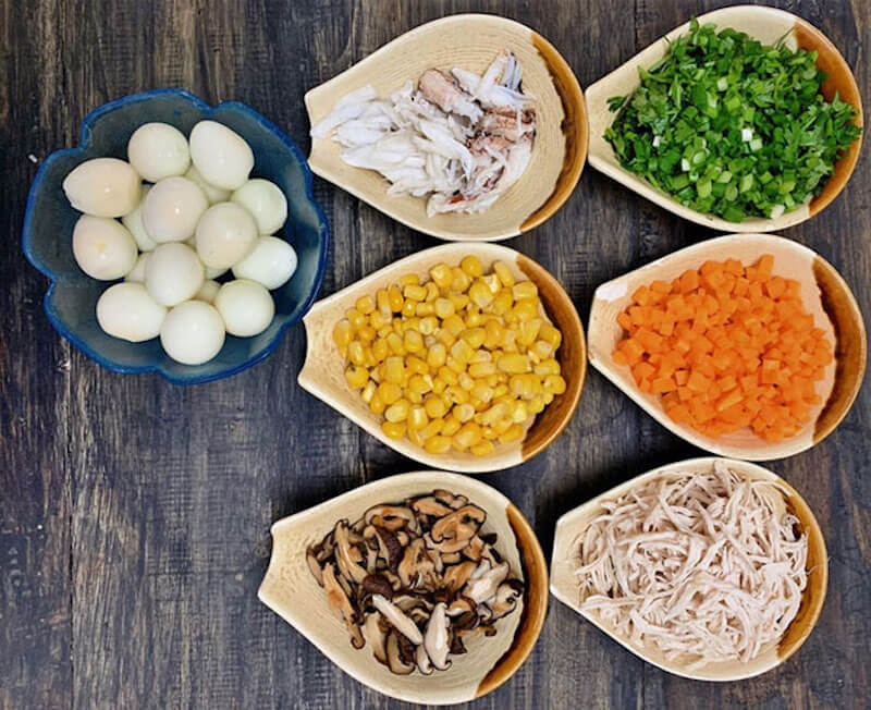 Các đĩa thức ăn gồm có trứng, bắp, sợi gà, cà rốt, hành