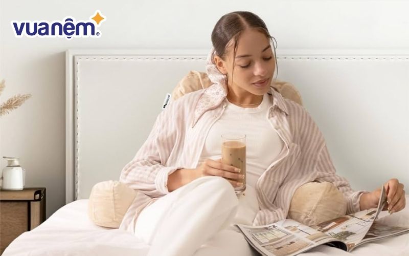 Ngồi trên giường với một chiếc gối kê sau lưng giúp giảm áp lực lên lưng